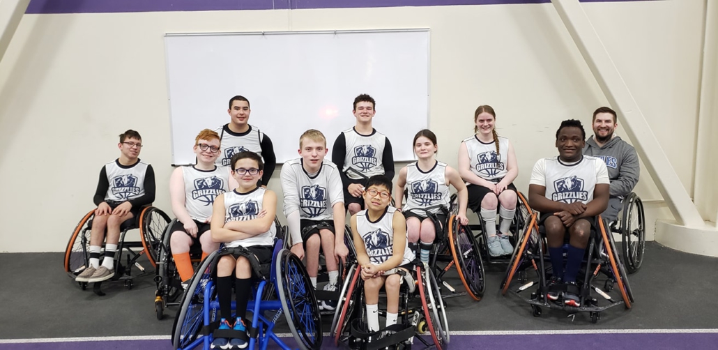 The youth wheelchair basketball team, the Grizzlies, lined up in their chairs, smiling at the camera.