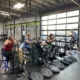 Four women working out next to each other. They are all seated and using a stationary bike with their arms.