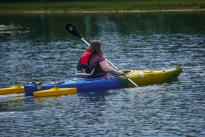 A woman sitting in a kayak with outriggers that help with balance.